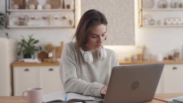 Frau surft mit Laptop im Internet und schreibt in Textbuch — Stockvideo