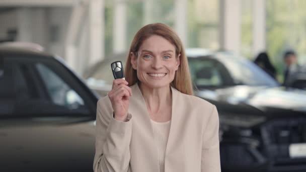 Frau posiert im Autosalon mit Schlüssel in der Hand — Stockvideo