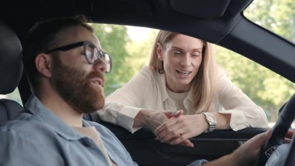 女性のディーラーは新しい車についての男性の顧客をコンサルティング — ストック動画