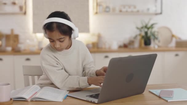 Bambino indiano che utilizza cuffie e laptop a casa — Video Stock