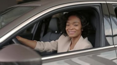 Gülümseyen Afrikalı kadın yeni arabanın salonunu inceliyor.