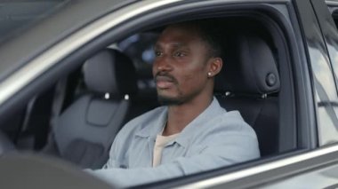 Anahtarları elinde olan neşeli Afrikalı adam yeni arabasında oturuyor.