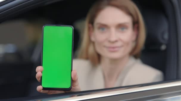 Žena sedí v autě v prodejně a drží smartphone — Stock video