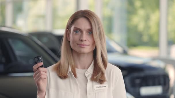 Усміхнена жінка позує в салоні з ключами від машини в руках — стокове відео