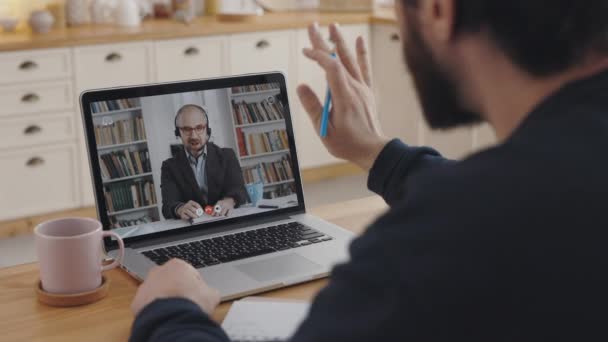 Mannelijke student begroeting tutor tijdens online les op laptop — Stockvideo