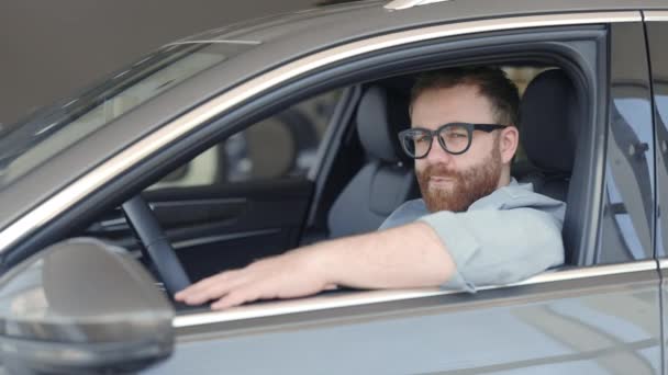 Веселый парень с ключами в руках сидит внутри своего нового авто — стоковое видео