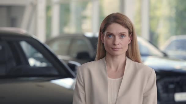 Retrato de una mujer bonita posando en un salón de autos moderno — Vídeos de Stock