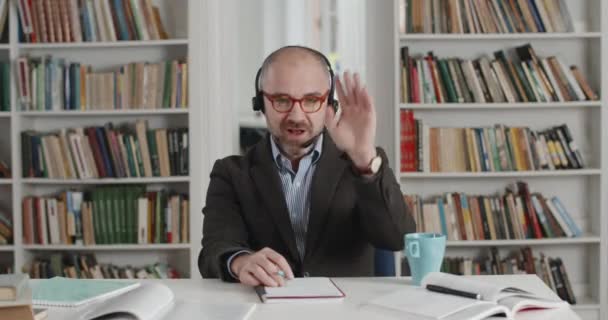 Starší učitel ve sluchátkách dávat přednášku podle video volání — Stock video