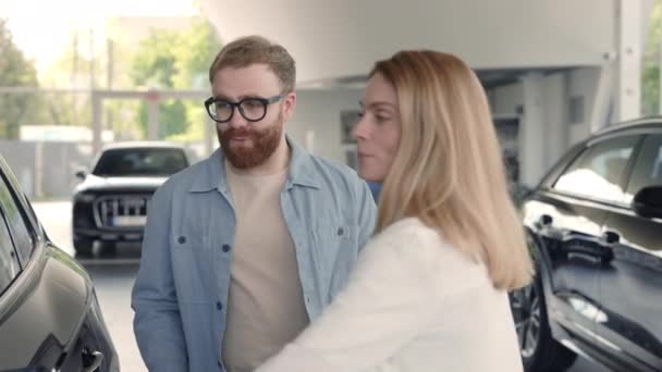 Mujer presentando coche de lujo en el salón para el cliente masculino — Vídeos de Stock