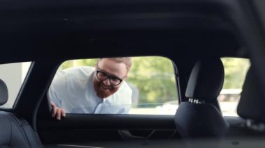 Satın almadan önce yeni arabanın tüm detaylarını inceleyen adam