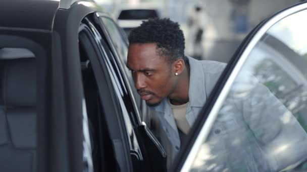Вид сбоку афроамериканского парня, наблюдающего за салоном современного автомобиля — стоковое видео