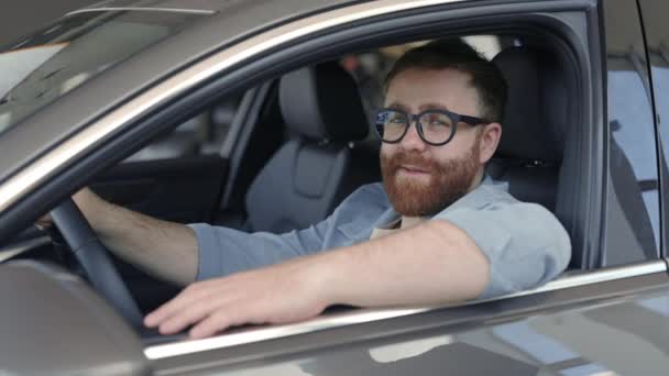 Homme heureux dans les lunettes assis dans la voiture et regardant la caméra — Video