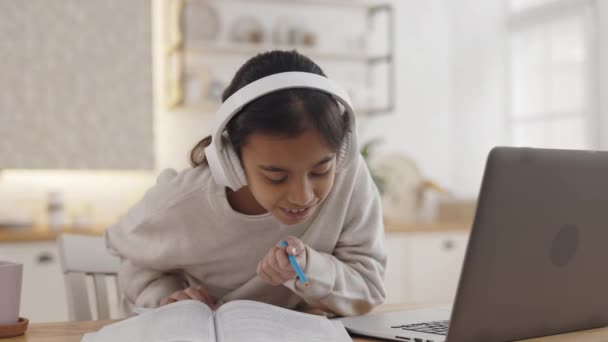 Meisje dat geniet van muziek in hoofdtelefoon tijdens afstandsonderwijs — Stockvideo