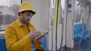 Metro vagonunda kitap okuyan yakışıklı adam.