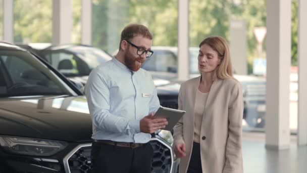 Mężczyzna sprzedawca z tabletką stojący w salonie z kobietą — Wideo stockowe