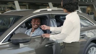 Kadın satıcı yeni araba sahibinden erkek sahibine anahtarları sunuyor.