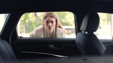 Bayilikte yeni arabanın içini inceleyen sevimli bir kadın.