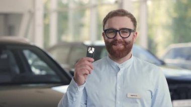 Araba galerisinde elinde anahtarlarla duran bir erkek satıcı.