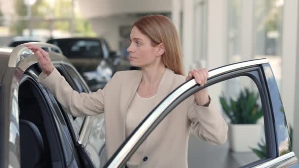 Mooie dame onderzoekt interieur van nieuwe auto in showroom — Stockvideo