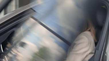 Kadın içeride otururken modern arabanın içini inceliyor.