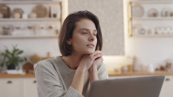 Urocza kobieta siedzi przy kuchennym stole z nowoczesnym laptopem — Wideo stockowe