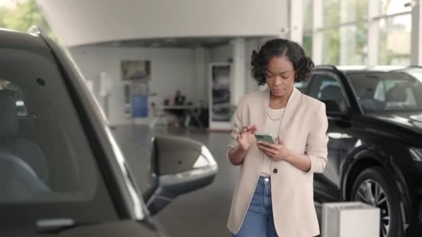 Dame africaine utilisant un smartphone tout en choisissant une nouvelle voiture — Video