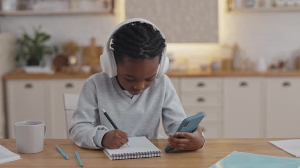 Bambino abbastanza africano che usa lo smartphone mentre studia a casa — Video Stock