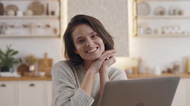 Estudante do sexo feminino sorridente sentado na mesa da cozinha com laptop — Vídeo de Stock