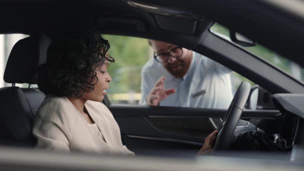 Dame africaine assis dans la voiture tandis que le concessionnaire masculin debout près — Video