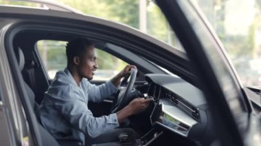 Modern arabanın içini inceleyen mutlu bir erkek müşteri.