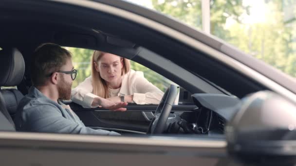 Vrouwelijke verkoper helpen mannelijke klant om nieuwe auto te kiezen bij salon — Stockvideo