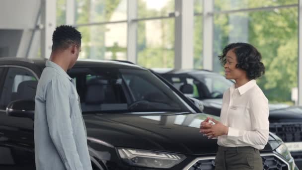 Prodavačka představující auto potenciálnímu klientovi v salonu — Stock video
