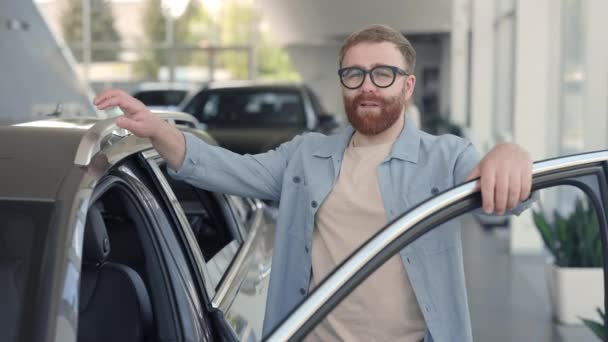 Hombre feliz en anteojos eligiendo nuevo vehículo en el centro del coche — Vídeos de Stock