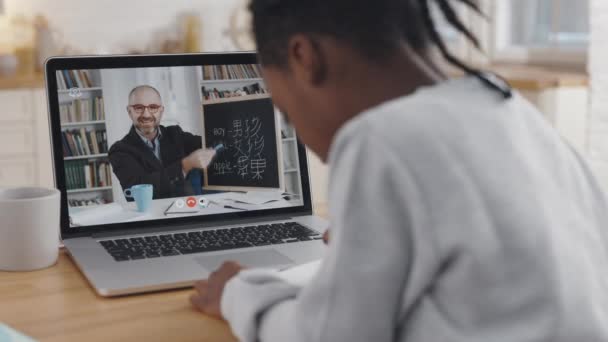 Lição de língua chinesa. Aluno africano tomar notas durante a aula virtual sobre laptop — Vídeo de Stock