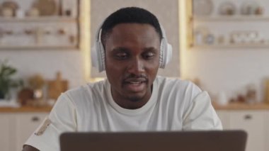 Afrikalı adam evde otururken online seminere katılıyor.