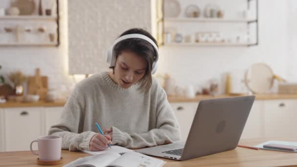 Mulher positiva navegando na internet no laptop e escrevendo notas — Vídeo de Stock