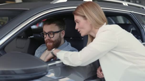 Comerciante do sexo feminino apresentando carro novo para o cliente masculino — Vídeo de Stock