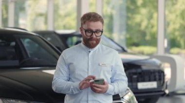 Akıllı telefon kullanarak araba tamirhanesinin yakışıklı erkek danışmanı.