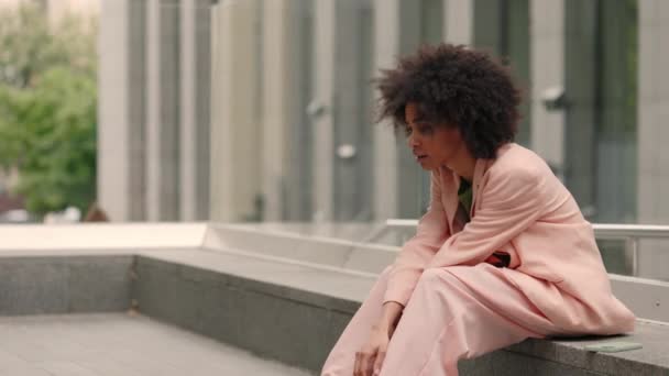 Zo teleurgesteld. Volledig uitzicht op de krullende multiraciale vrouw die zich verdrietig en teleurgesteld voelt terwijl ze aan de trap zit en huilt. Mensen emoties concept. — Stockvideo