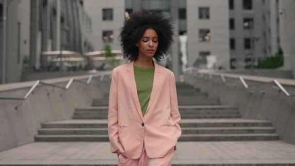 Encantadora jovem mulher multirracial moderna com cabelo preto andando na rua e olhando para a câmera para fotografar ao ar livre. Conceito de beleza, moda e modelos. — Vídeo de Stock