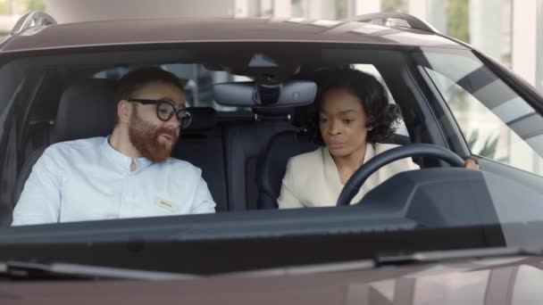 Vrouw testen van moderne auto terwijl zitten binnen met dealer — Stockvideo