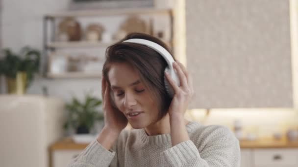Evde kulaklıkla müzik dinleyen olumlu bir kadın. — Stok video