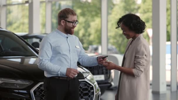 Salon manager presenting keys from new car to female owner — Stock Video