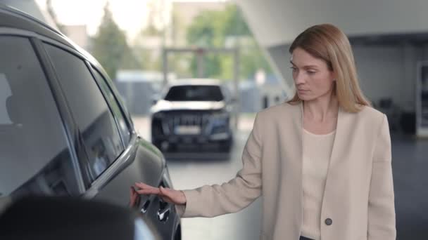 Bonita senhora tocando superfície do carro de luxo no salão de auto — Vídeo de Stock