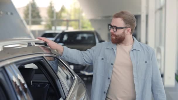 Hombre guapo examinando nuevo modelo de coche en la concesionaria — Vídeos de Stock