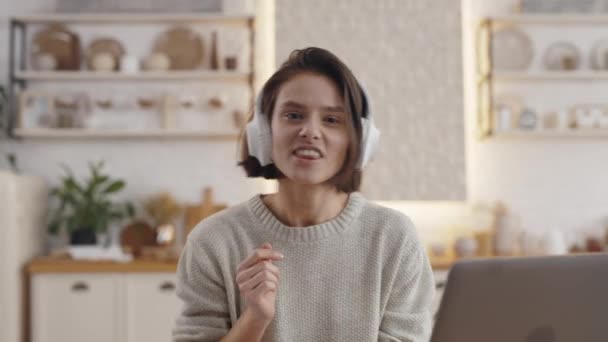 Vrouw genieten van lied in hoofdtelefoon tijdens het studeren op laptop — Stockvideo