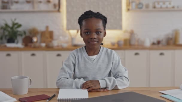 Afrikalı okul çocuğu elinde kitap ve notlarla masada oturuyor. — Stok video