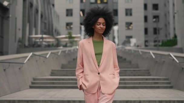 Encantadora joven mujer multirracial moderna con el pelo negro caminando por la calle y mirando a la cámara para la sesión de fotos al aire libre. Concepto de belleza, moda y modelos. — Vídeos de Stock