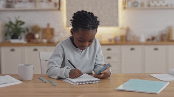 African american child écrit des notes et utilise un smartphone — Video