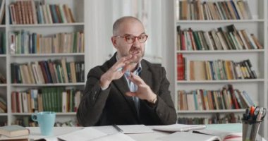 Video konferansı sırasında ders açıklayan olgun öğretmen